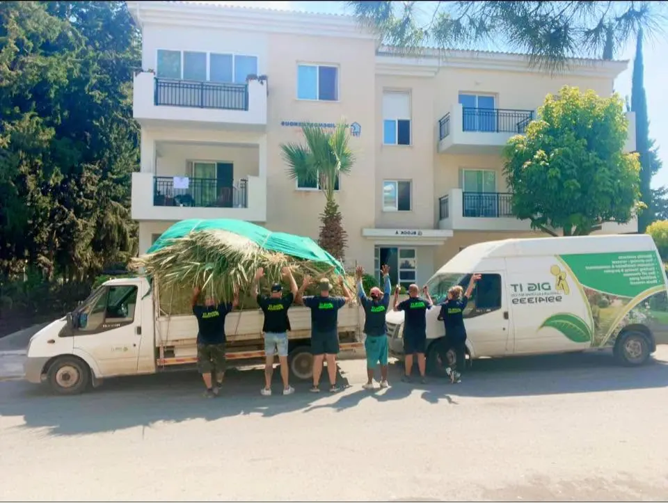 The crew cheering beside a van loaded with palm fronds at an apartment complex