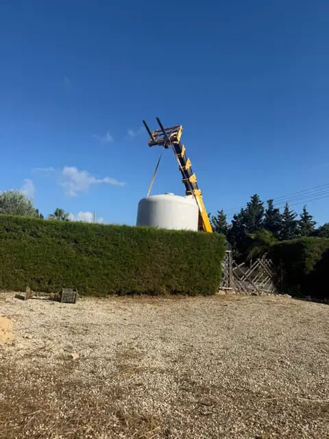 Telehandler reaching over a tall hedge