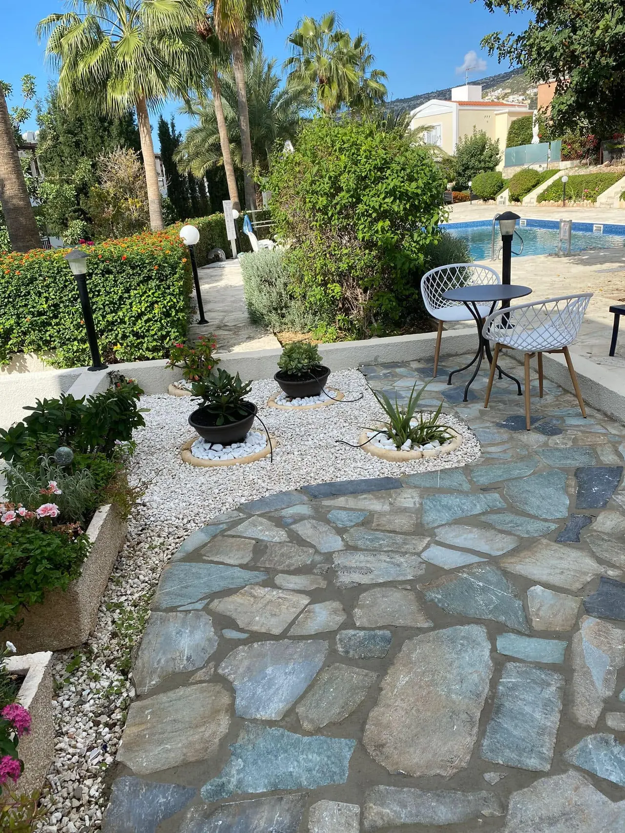 Stone patio garden with white gravel, pots and bistro chairs